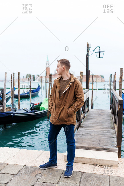 Young blond guy in a brown jacket in middle of streets of Venice