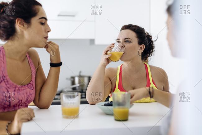 Content diverse sportive women having healthy snack at home