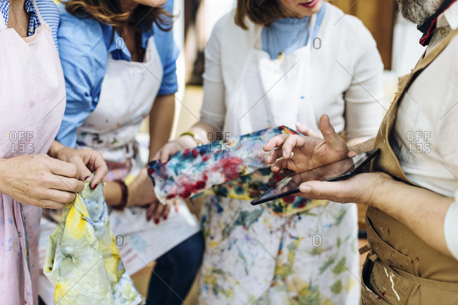 Crop artisans with gadget discussing textile design in workshop