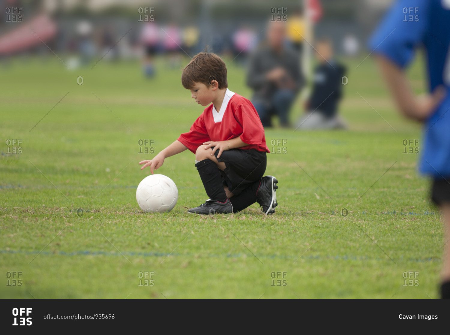 Young boy touching a soccer ball with his finger on a soccer field