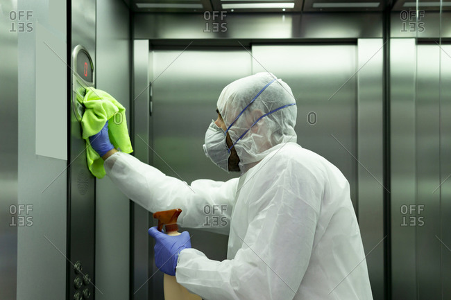 Coronavirus. Worker disinfecting hospital elevator to avoid contagion.