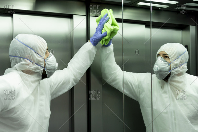 Coronavirus. Worker disinfecting hospital elevator to avoid contagion.