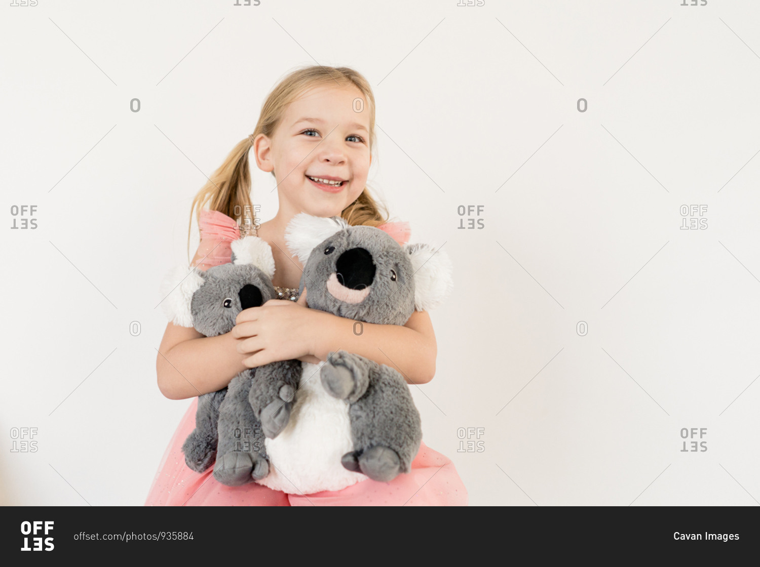 Cute blond little girl hugging koala stuffed animals indoors
