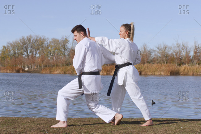 Young girl and young boy karate experts practice and fight by the water