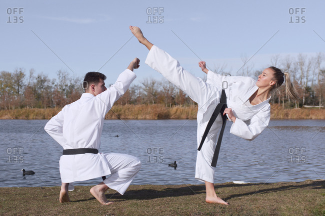 Young girl and young boy karate experts practice and fight by the water