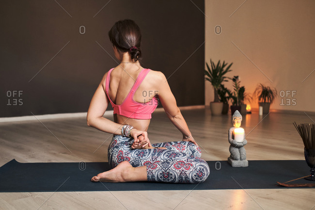Young woman doing yoga on yoga mat in atmospheric yoga studio