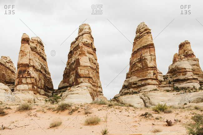 Four sandstone towers against gray skies in the desert of Utah