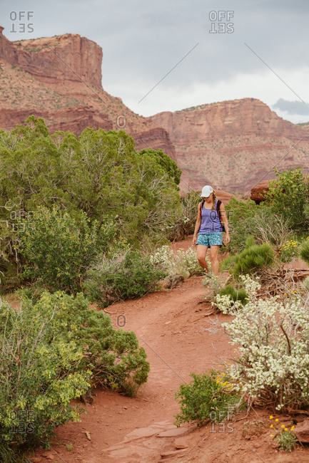 Woman hiker in shorts and a tank top walks amongst desert shrubbery