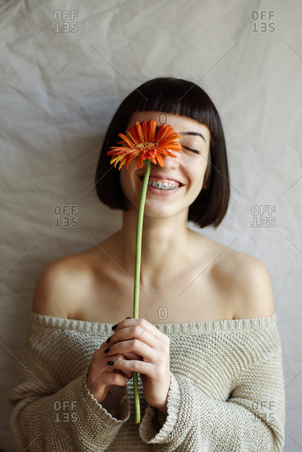 Studio portrait of a young beautiful woman with a flower in front of her face