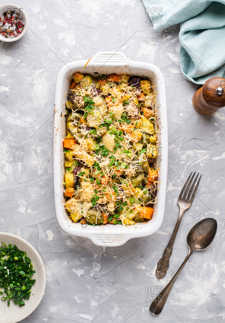 Overhead view of vegetarian casserole dish with potatoes, brussel sprouts, carrot and cheese
