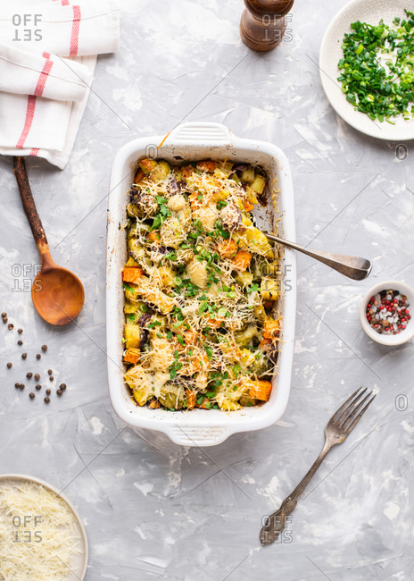 Overhead view of vegetarian casserole dish with potatoes, brussel sprouts, carrot and cheese
