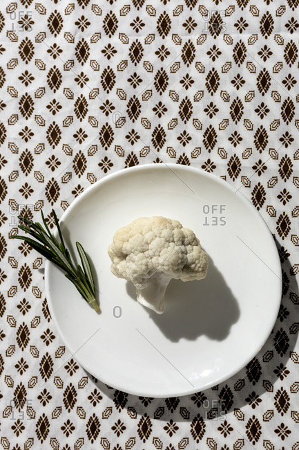 Raw cauliflower bouquet with rosemary from above with sunlight. Flat lay. Top view