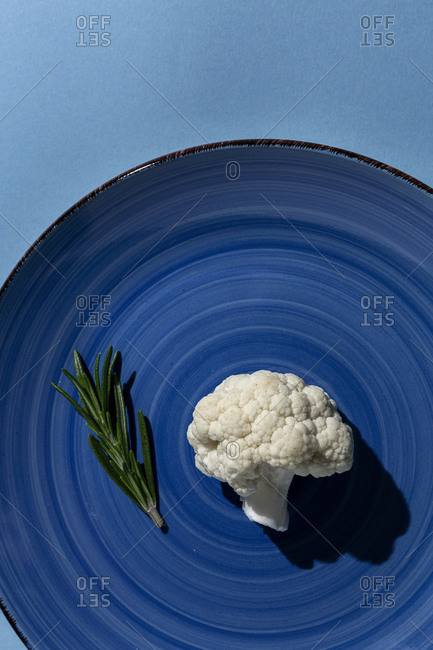 Raw cauliflower bouquet with rosemary from above with sunlight. Flat lay. Top view