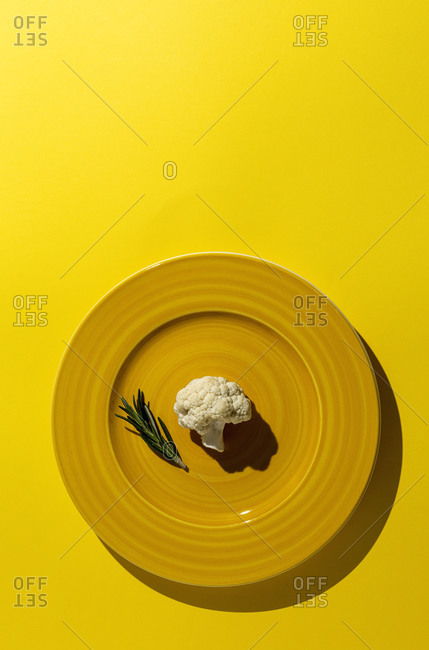 Raw cauliflower bouquet with rosemary from above with sunlight. Flat lay. Top view