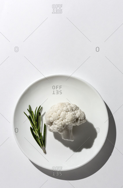 Raw cauliflower bouquet with rosemary from above with sunlight. Flat lay. Top view