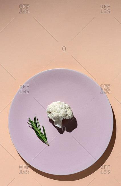 Raw cauliflower bouquet with rosemary from above with sunlight. Flat lay. Top view
