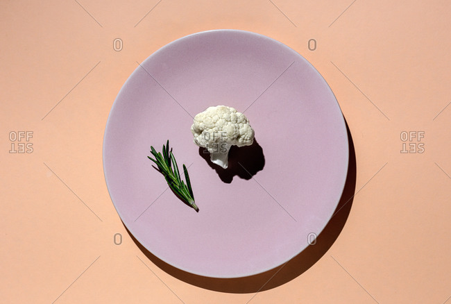 Raw cauliflower bouquet with rosemary from above with sunlight. Flat lay. Top view