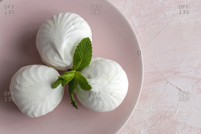 From above top view of homemade white Zefir traditional russian dessert with mint on pink background