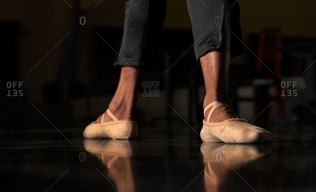 Unrecognizable crop professional ballet dancer foot on tiptoe wearing pointe ballet shoes in a modern studio