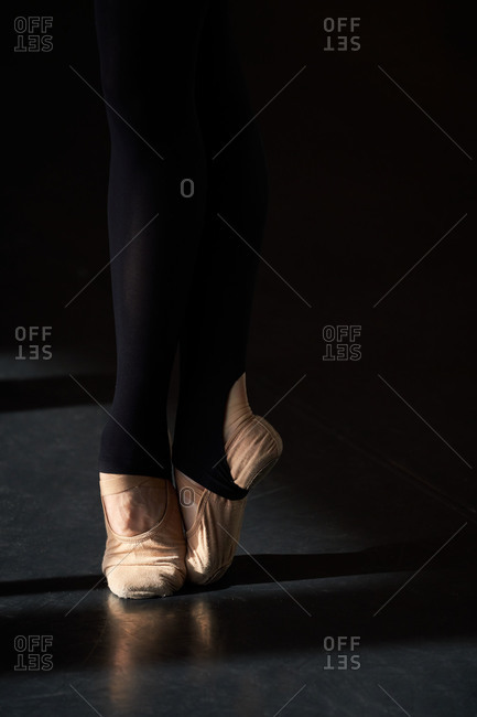 Unrecognizable crop professional ballet dancer foot on tiptoe wearing pointe ballet shoes in a modern studio