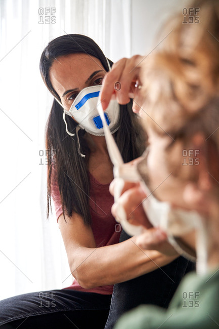 Mother putting on a respirator for her child to avoid possible infection