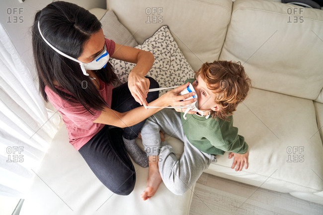 Mother putting on a respirator for her child to avoid possible infection