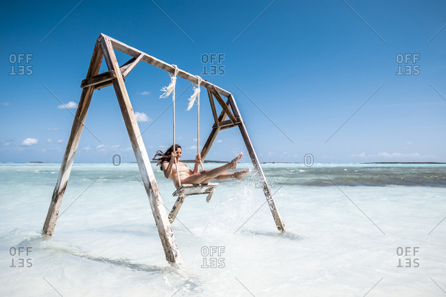 Woman swinging on swing in the sea- Bahamas- Caribbean