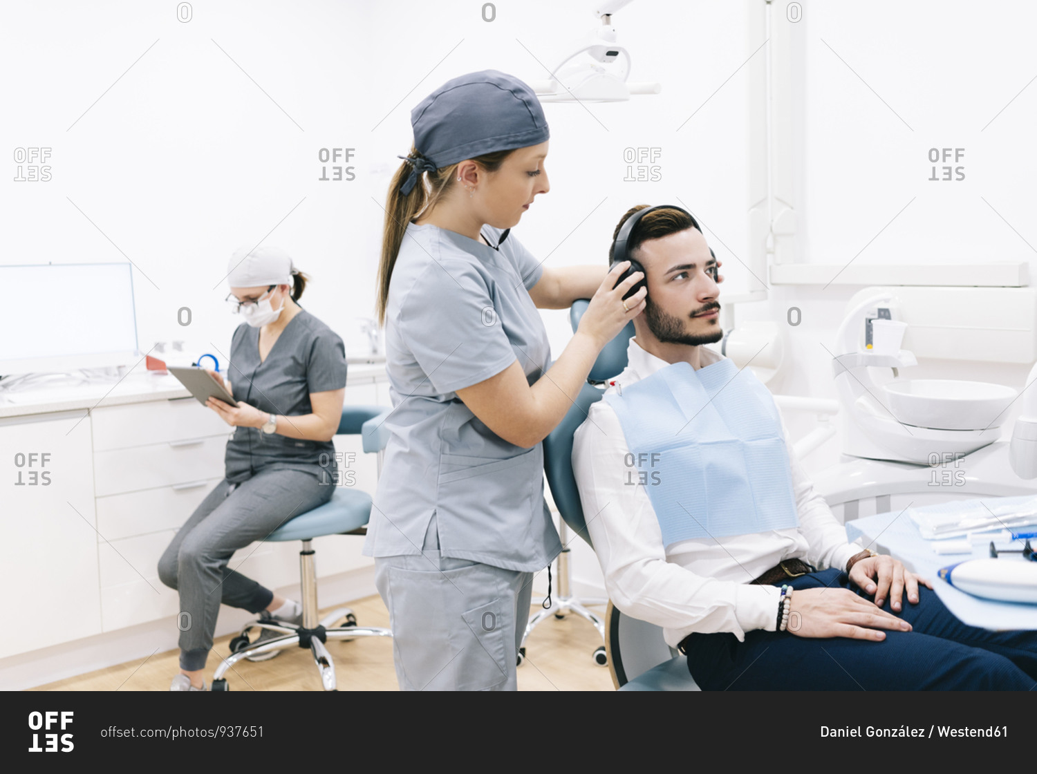 Medical secretary preparing dental treatment putting on headphones on patient\'s head