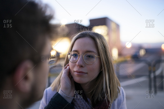 Portrait of blond young woman face to face with her boyfriend at evening twilight