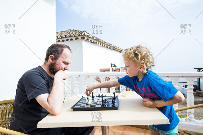 Father and son playing chess on roof terrace- Spain