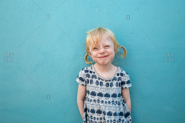 Portrait of grinning little girl in front of blue wall