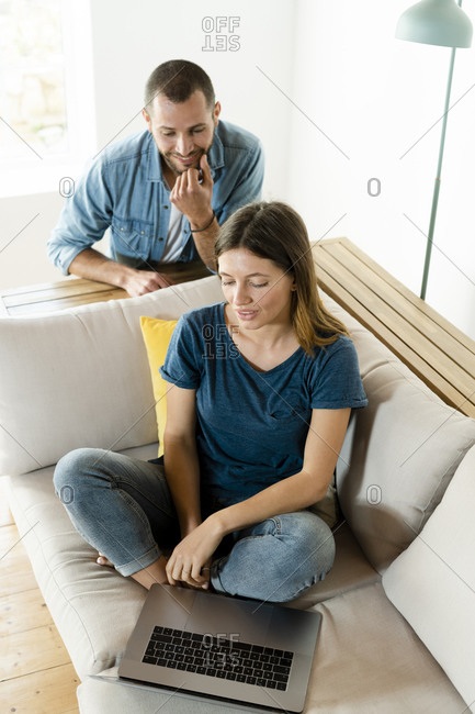Young couple on couch at home with laptop
