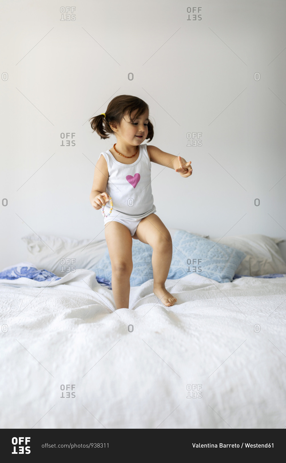 Portrait of little girl in underwear dancing on bed stock photo