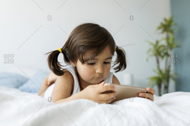Portrait of little girl lying on bed in underwear looking at