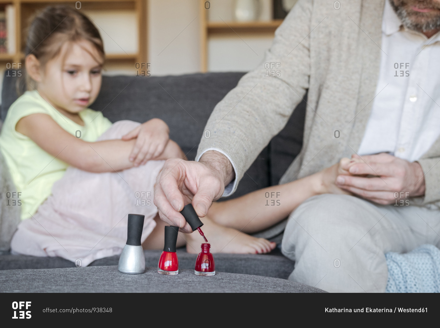 Crop view of father painting his daughter's toenails with red nail