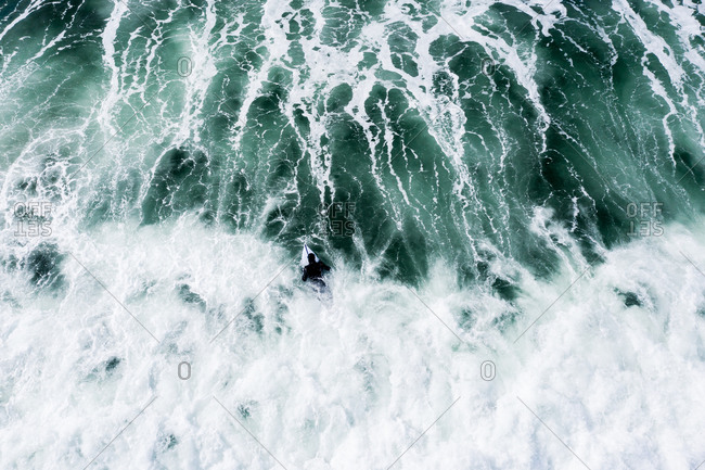 Aerial view of surfer riding turquoise waves in the ocean