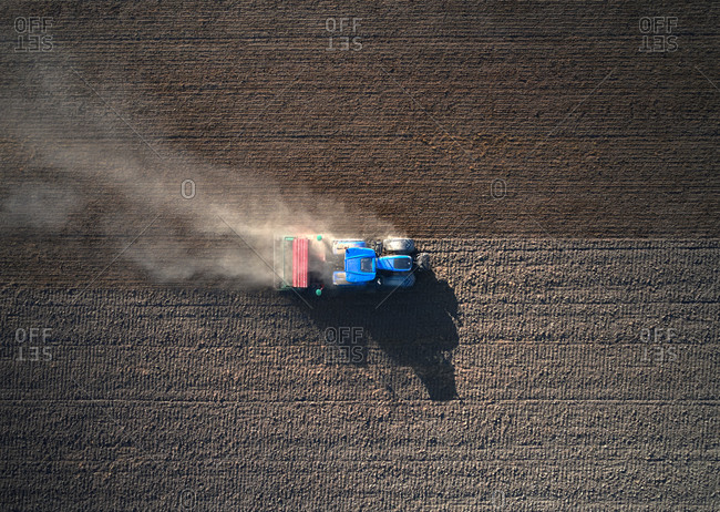 Aerial view of a blue and red tractor ploughing the earth, Rosasco, Lombardy, Italy.