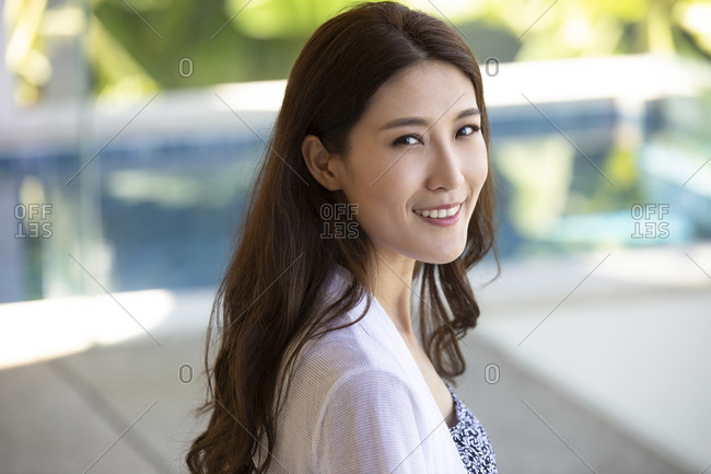 Happy young Chinese woman relaxing on balcony