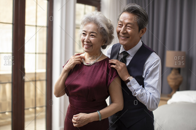 Happy senior Chinese couple getting dressed at home