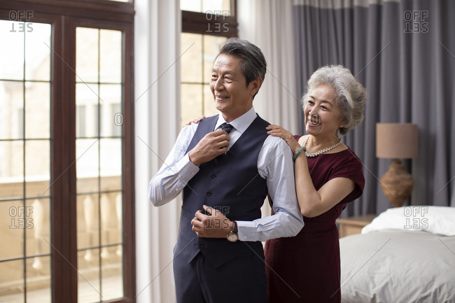 Happy senior Chinese couple getting dressed at home
