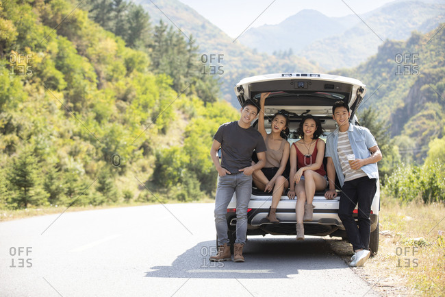 Happy young Chinese friends enjoying road trip