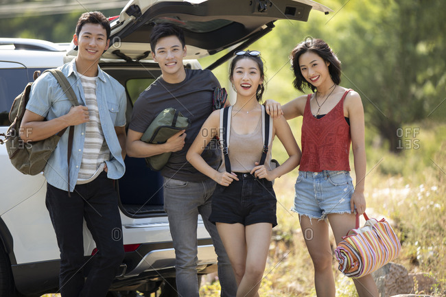 Happy young Chinese friends camping outdoors
