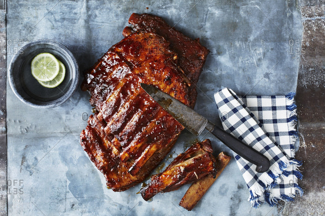 Still life with BBQ spare ribs and kitchen knife, overhead view