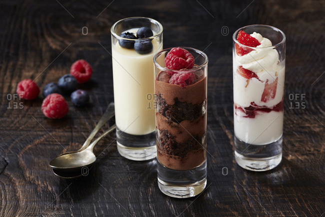 Still life with three desserts in glasses with raspberry and blackberry garnish