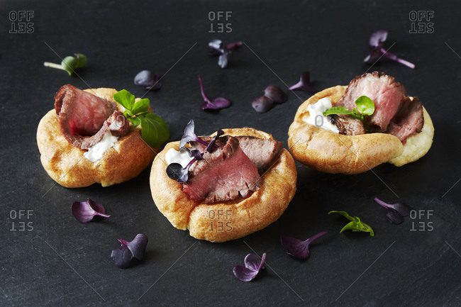 Still life with canapes of roast beef in yorkshire puddings on black slate