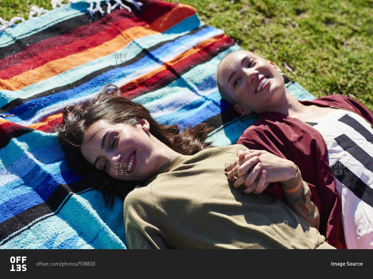 Two young female friends lying on picnic blanket in park, Los Angeles, California, USA