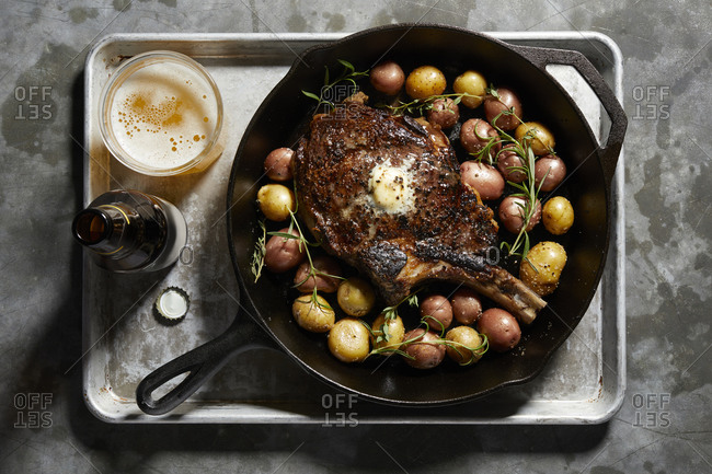 Skillet with large tomahawk steak & potatoes, overhead view