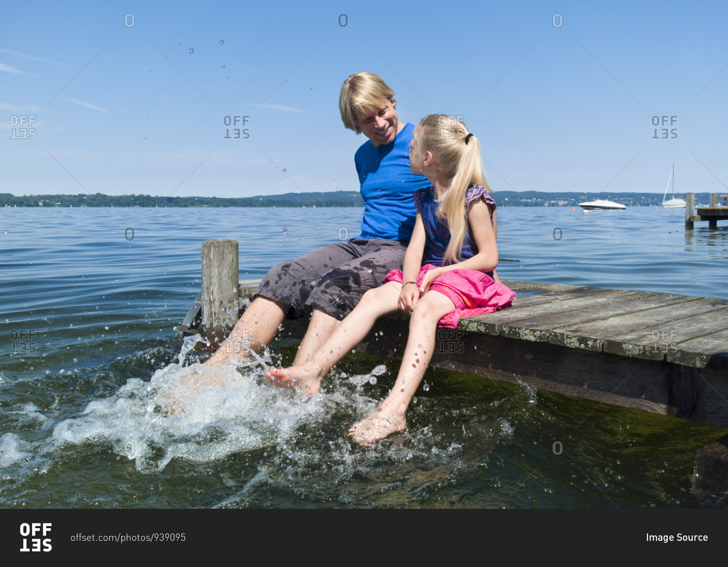 Father and daughter cooling feet in water, Lake Starnberg, Bavaria, Germany