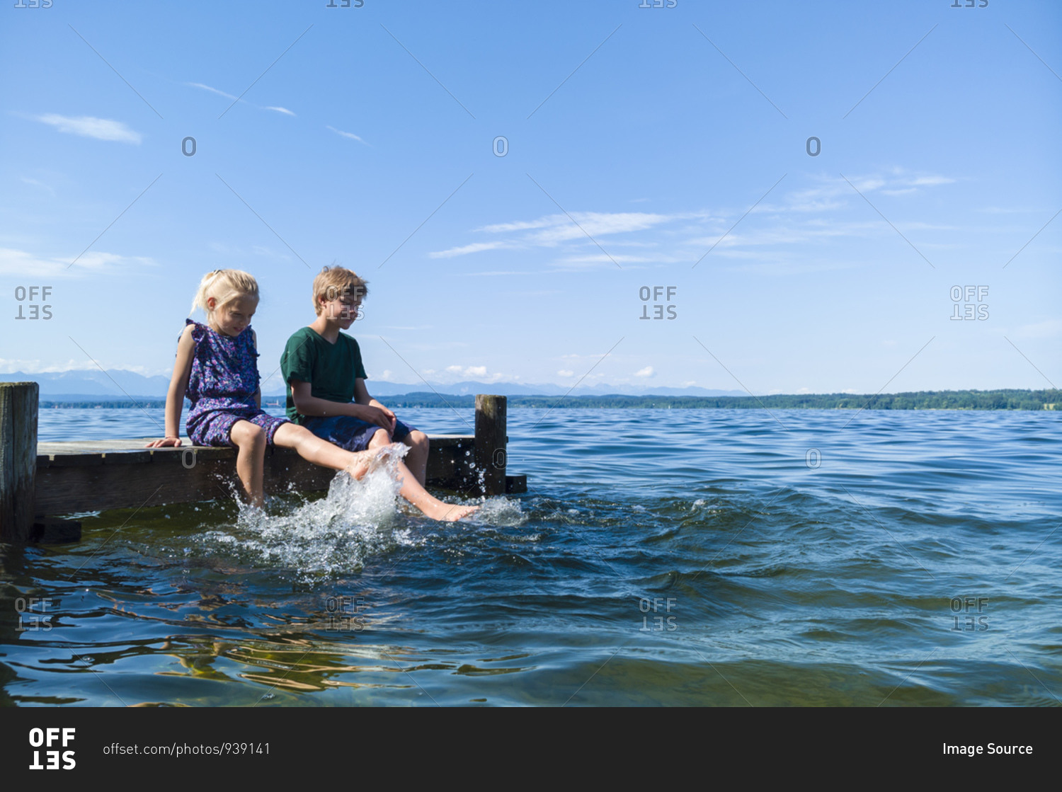 Siblings cooling feet in water, Lake Starnberg, Bavaria, Germany