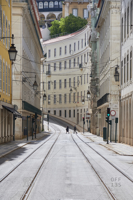 Two people in the distance on empty street, the rua da Conceicao in Lisbon during the pneumonia outbreak by the new Coronavirus
